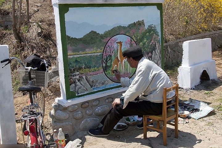 Một nghệ sĩ đang hoàn thành bức tranh bên đường