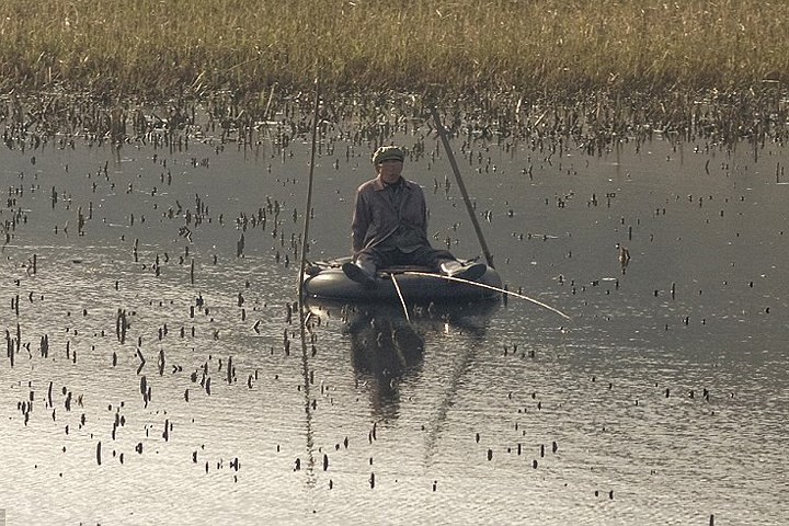 Câu cá trong hồ nhỏ ở nông thôn. Đây là 1 cách để có thức ăn tươi ở vùng sâu vùng xa. Trong ảnh, người đàn ông dùng săm ô tô cũ làm thuyền.