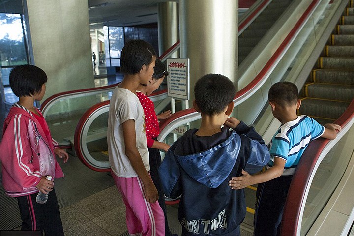Một số trẻ em từ nông thôn ra có mặt ở Trại Thiếu nhi Songdowon tỏ ra e dè khi đứng trước hệ thống thang cuốn mà các em chưa từng thấy trước đó.