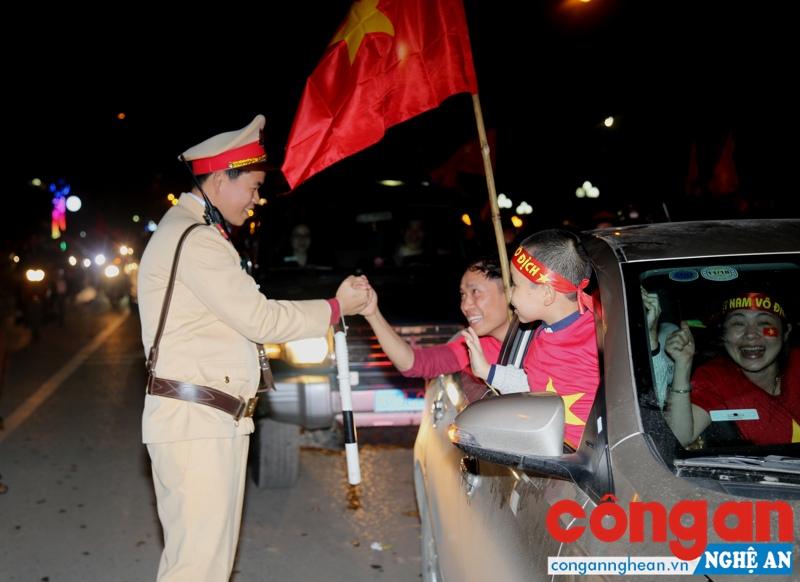 Chiến sĩ CSGT chia vui cùng người dân đang đổ ra đường ăn mừng sau chiến thắng của U23 Việt Nam.