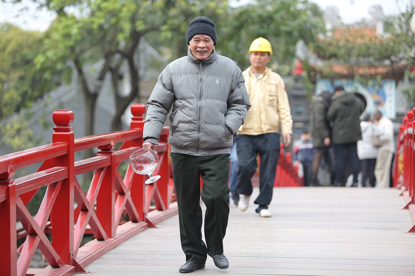 Một người đàn ông lớn tuổi đi qua cầu Thê Húc để thả cá trong khu vực đền Ngọc Sơn