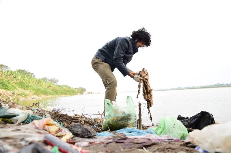 Một bạn trẻ người nước ngoài dọn rác ở sông Hồng