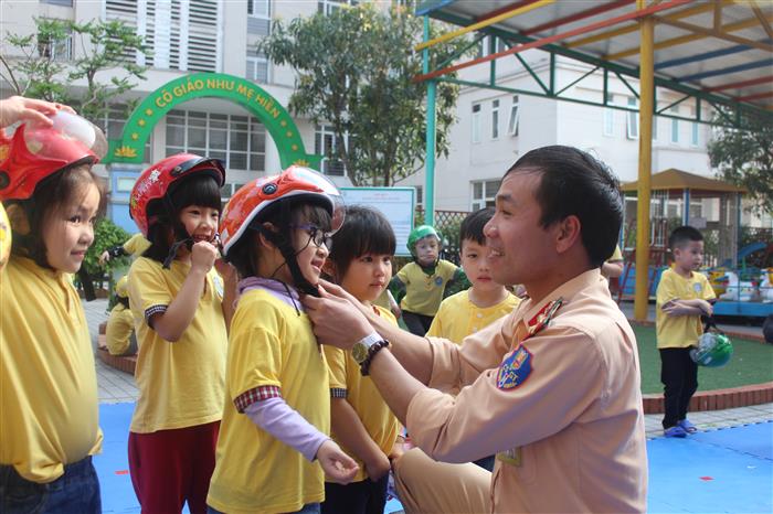 Cán bộ Phòng CSGT hướng dẫn trẻ đội mũ bảo hiểm  