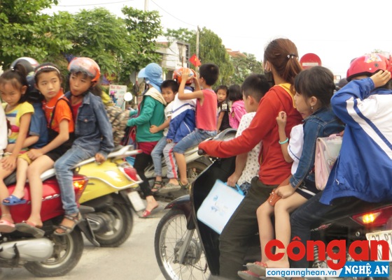 Hàng chục trẻ em không đội mũ bảo hiểm khi ngồi trên xe gắn máy - (Ảnh chụp trên Quốc lộ 1A đoạn qua xã Diễn Kỷ, huyện Diễn Châu)