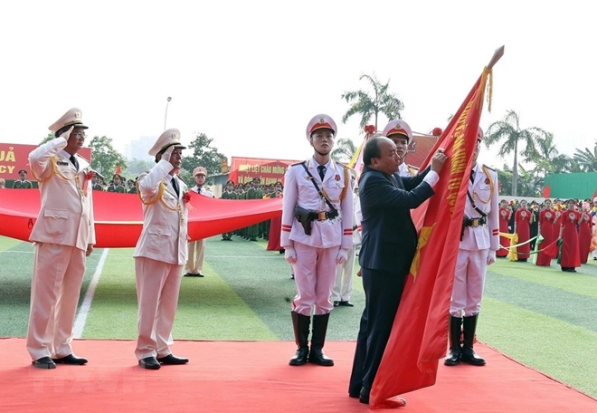 Thủ tướng Nguyễn Xuân Phúc gắn huy hiệu Anh hùng lực lượng vũ trang nhân dân thời kỳ kháng chiến chống Mỹ cứu nước lên lá Cờ truyền thống của Học viện CSND.