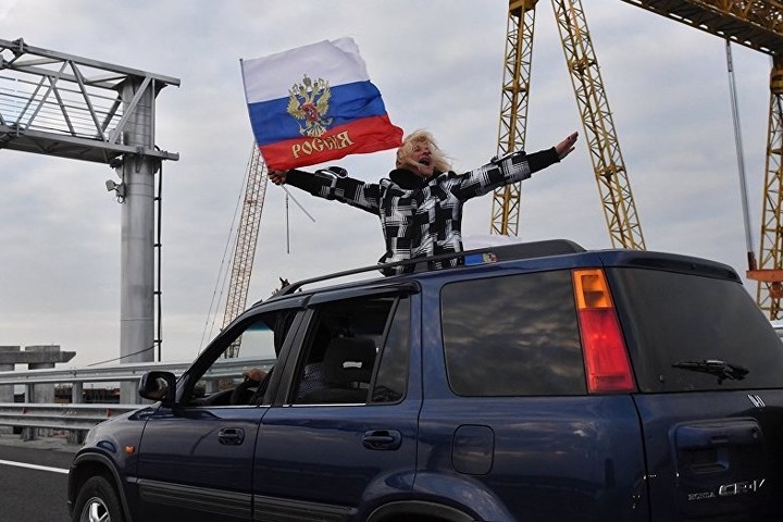 Người dân phấn khích cầm biểu tượng Nga đi ô tô qua cầu Eo biển Kerch. Ảnh: Sputnik.