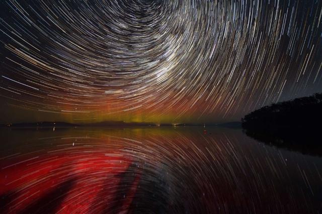 Hình ảnh phơi sáng lâu tạo ra hình ảnh đáng kinh ngạc khi những ngôi sao di chuyển tạo thành những vòng tròn đồng tâm cùng cực quang màu đỏ đang tỏa sáng ở nền trời phía sau. Ảnh: Pat Law Photography/Getty Images.