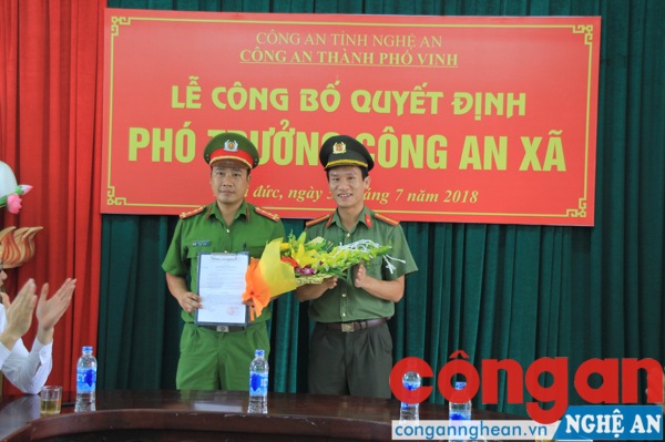 Đồng chí Lê Đức Dũng – Phó trưởng Công an TP Vinh trao quyết định và tặng hoa chúc mừng đồng chí Đàm Ngọc Hưng
