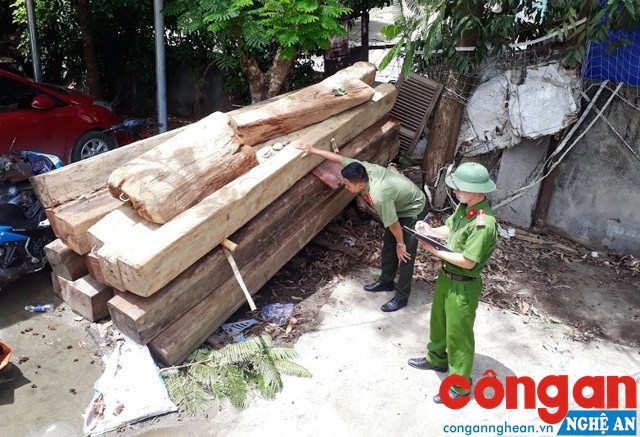 Cán bộ Công an huyện kiểm tra số gỗ không rõ nguồn gốc bị tạm giữ