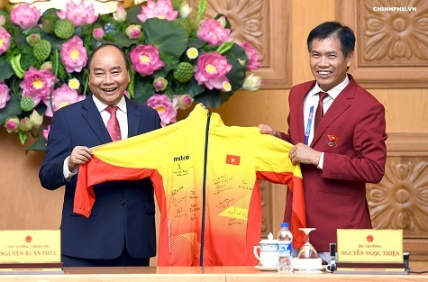 Thủ tướng nhận quà là chiếc áo đồng phục của Đoàn thể thao Việt Nam có chữ ký của các vận động viên đoạt huy chương tại ASIAD - Ảnh: VGP/Quang Hiếu