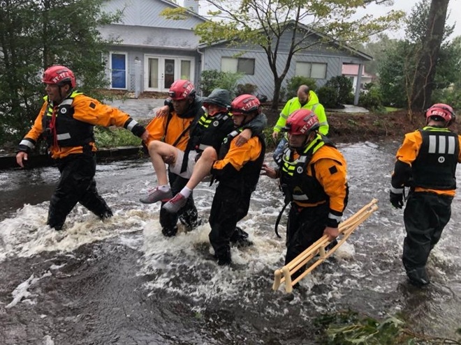 Nhân viên cứu hộ đang trợ giúp một người đàn ông cao tuổi ra khỏi khu vực ngập lụt tại thị trấn River Bend.