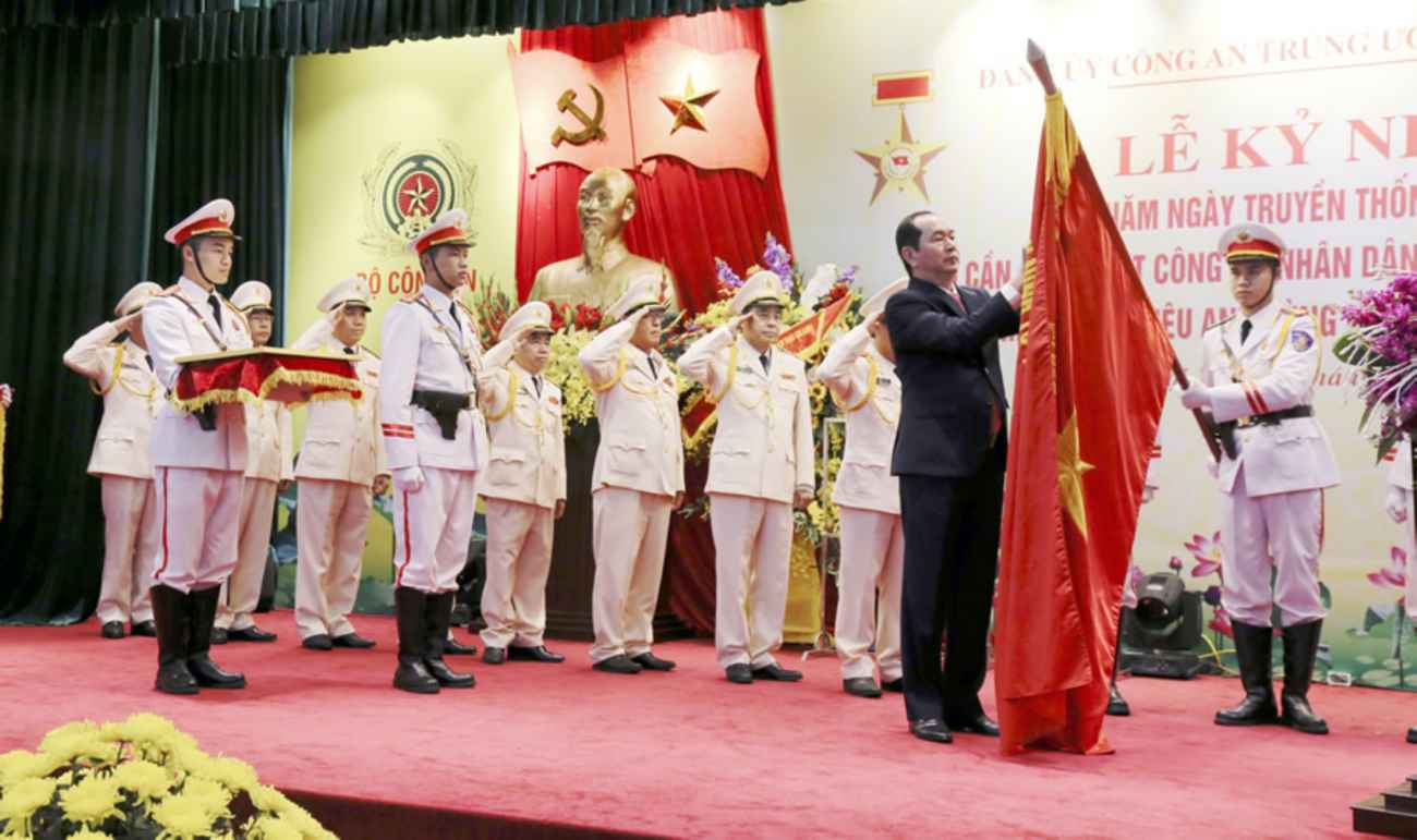 Chủ tịch nước Trần Đại Quang gắn Huy hiệu lên Cờ truyền thống của Tổng cục HC- KT CAND tại Lễ kỷ niệm 70 năm Ngày truyền thống lực lượng Hậu cần- Kỹ thuật CAND (25-1-1948 - 25-1-2018). Ảnh: Bộ Công an