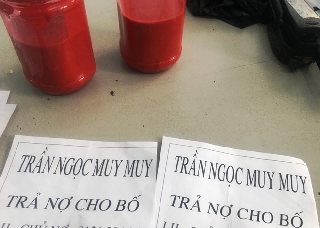 Hai bình sơn đỏ và tờ giấy đòi nợ các đối tượng dự định mang đến nhà ông Trần Ngọc M.M.