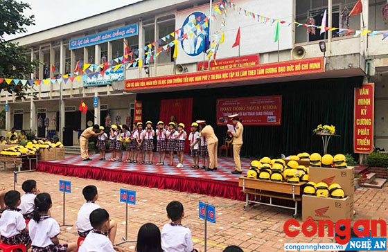 Cán bộ Công an TP Vinh trao tặng mũ bảo hiểm cho các em học sinh Trường Tiểu học Nghi Phú 2