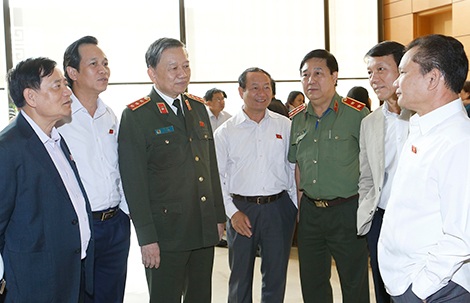 Bộ trưởng Tô Lâm trao đổi với các đại biểu bên hành lang Quốc hội, chiều 6-11.