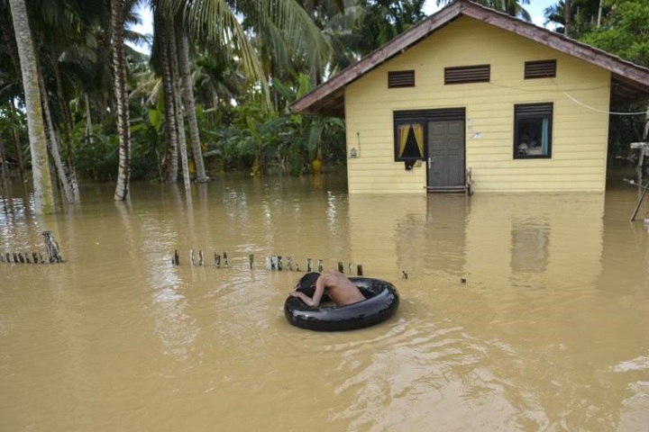 Một cậu bé Indonesia phải dùng một chiếc xăm xe ô tô làm phao bơi khi ngôi nhà của cậu đã chìm trong nước lũ do mưa lớn ở Teunom, tỉnh Aceh ngày 16/10/2018. Ảnh: AFP