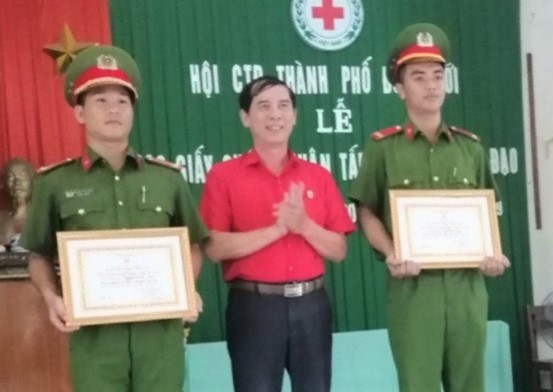 Chủ tịch Hội chữ thập đỏ thành phố Đồng Hới trao giấy chứng nhận tấm lòng vàng nhân đạo cho Trung úy Nguyễn Thanh Thiện và Trung sỹ Lê Đức Chính.