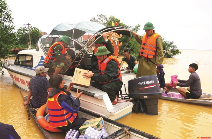 Cán bộ, chiến sĩ Ban Chỉ huy quân sự huyện Quảng Bình, tỉnh Quảng Bình vượt lũ hỗ trợ lương thực cho người dân xã Tân Ninh