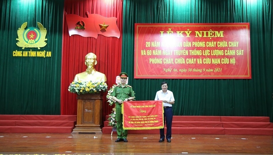 Đồng chí Lê Hồng Vinh trao bức trướng của UBND tỉnh Nghệ An tặng lực lượng PCCC&CNCH Công an Nghệ An. Bức trướng mang dòng chữ: 'Lực lượng Cảnh sát PCCC&CNCH Công an tỉnh Nghệ An - 60 năm xây dựng, chiến đấu và trưởng thành'