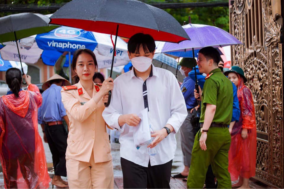 Nữ cán bộ CSGT che mưa giúp một thí sinh quên mang ô 