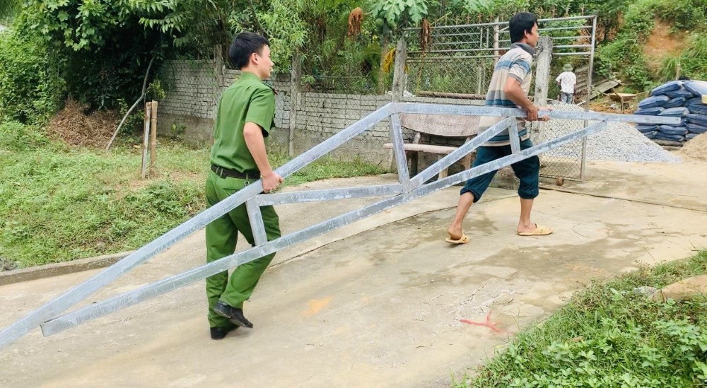Cán bộ Công an huyện Tương Dương cùng người dân vận chuyển vật liệu để dựng nhà cho người dân