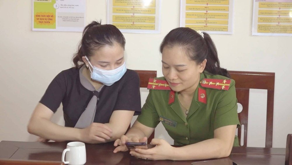 Cán bộ Công an xã Nghi Trung hướng dẫn công dân thao tác khai báo tạm trú, tạm vắng trực tuyến trên điện thoại.