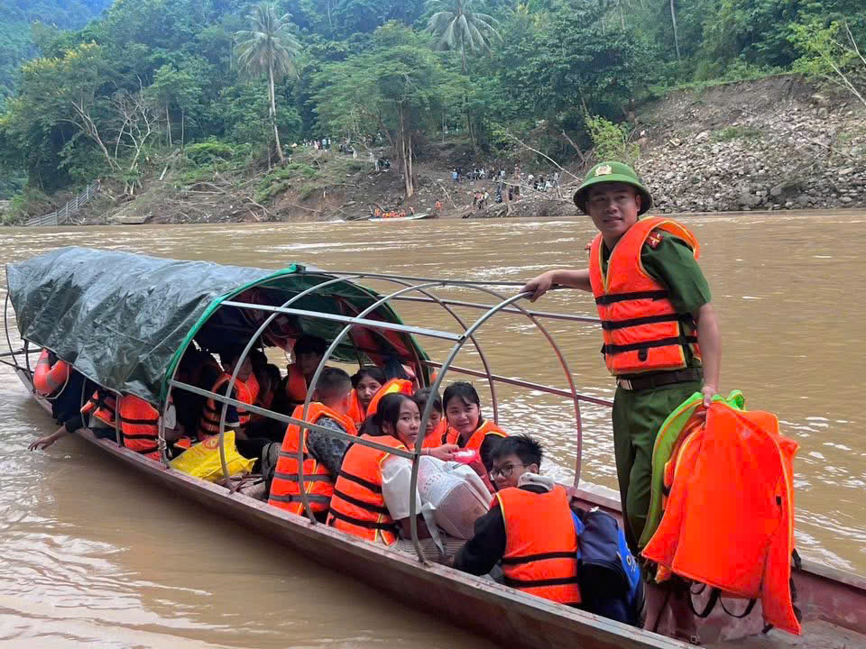 Cán bộ Công an xã di chuyển bằng thuyền đưa các bạn nhỏ qua sông