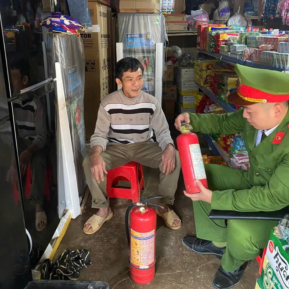 Công an xã hướng dẫn chủ cơ sở kiểm tra và thao tác sử dụng bình chữa cháy đúng cách để xử lý sự cố ban đầu
