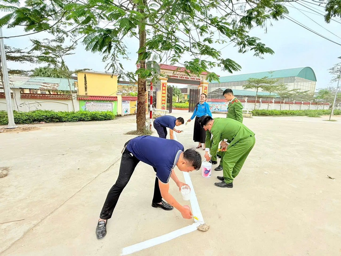 Công an xã phối hợp đoàn viên, thanh niên và giáo viên kẻ vạch khu vực trước cổng trường