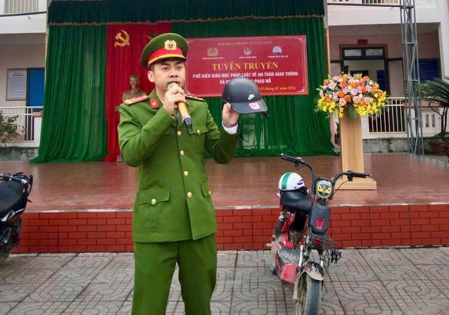 Cán bộ Công an xã hướng dẫ đội mũ bảo hiểm đúng cách