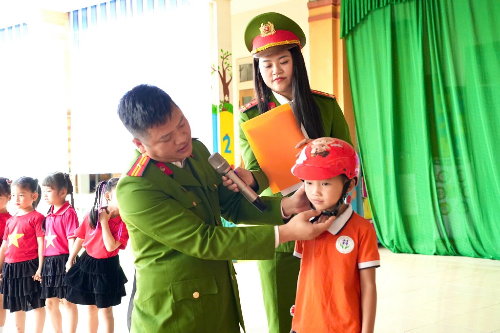Công an xã hướng dẫn đội mũ bảo hiểm đúng cách