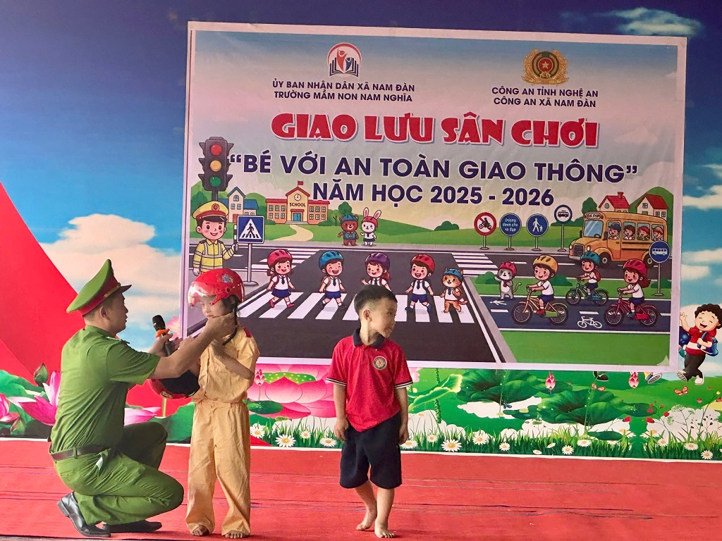 Công an xã Nam Đàn hướng dẫn trẻ đội mũ bảo hiểm khi tham gia giao thông