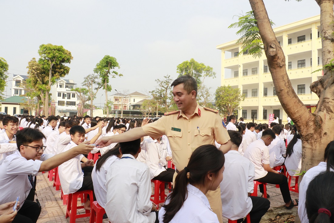 Đại diện Cục CSGT và Phòng CSGT tặng tờ rơi và bút gắn logo tuyên truyền pháp luật về trật tự an toàn giao thông đến học sinh