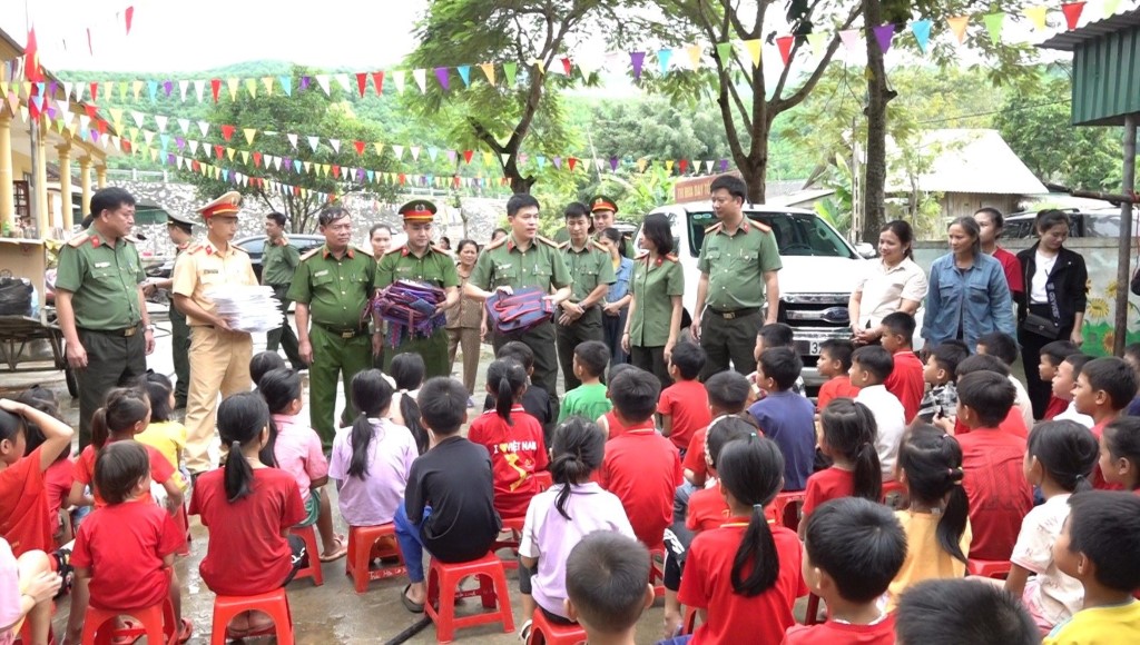 Đại tá Trần Hồng Quang – Phó Giám đốc Công an tỉnh  trao quà cho các em học sinh bị nước lũ cuốn trôi sách vở, đồ đạc