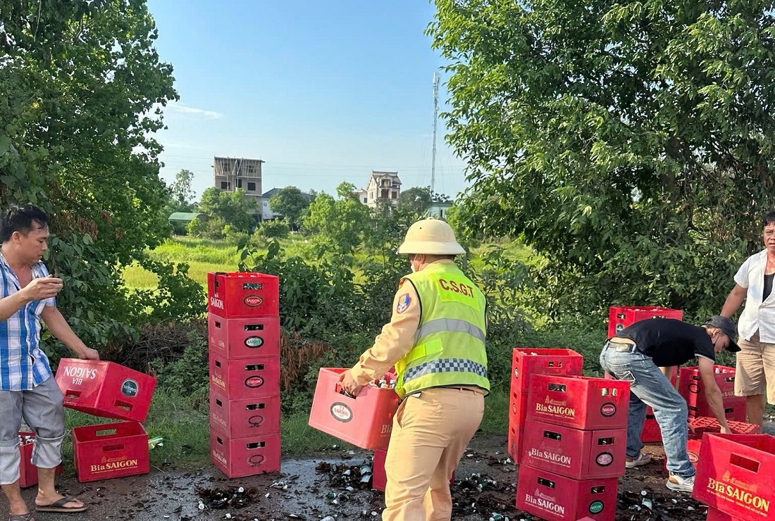 Tổ CSGT đường bộ số 5 cùng người dân giúp đỡ lái xe thu dọn số bia chai bị vỡ trên đường