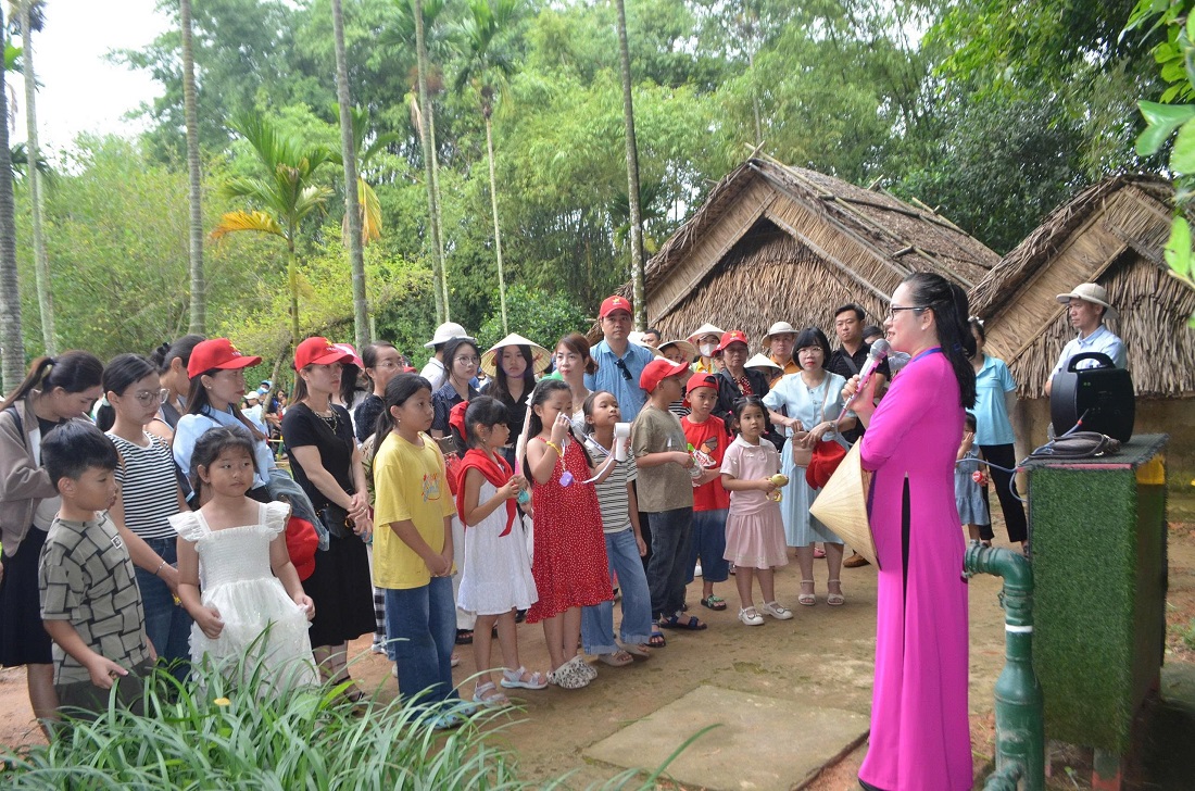 Các cháu và thân nhân nghe thuyết minh về quê Bác