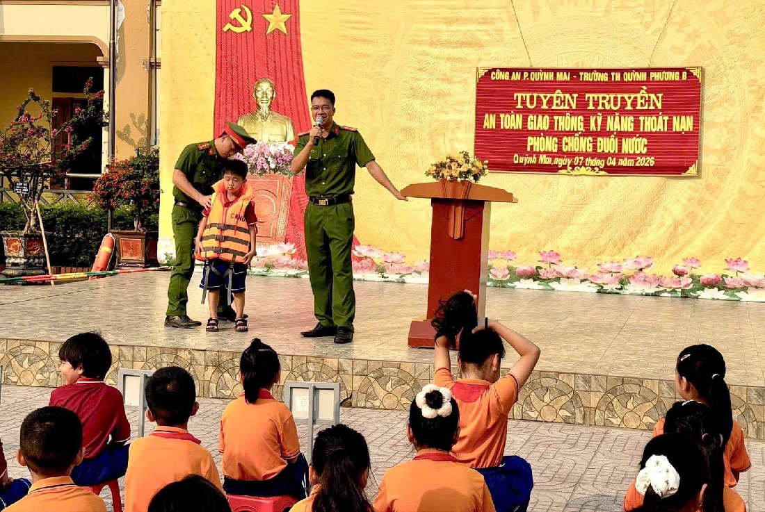 Công an phường Hoàng Mai hướng dẫn học sinh đội mũ bảo hiểm và mặc áo phao đúng cách