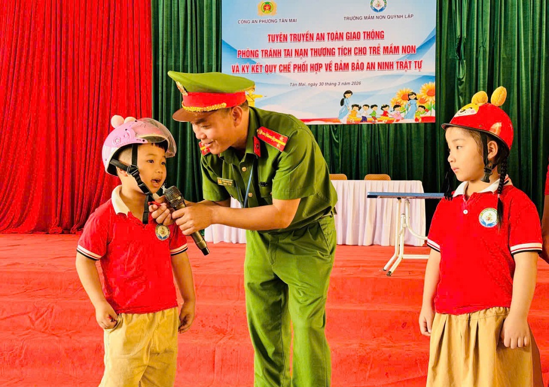 Công an phường hướng dẫn trẻ đội mũ bảo hiểm đúng cách