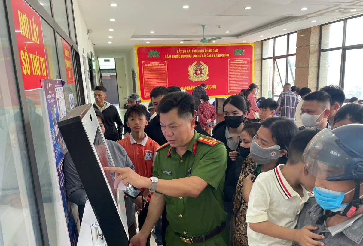 Cán bộ tại Bộ phận một cửa Công an tỉnh hướng dẫn người dân lấy số thứ tự. Ảnh: PV