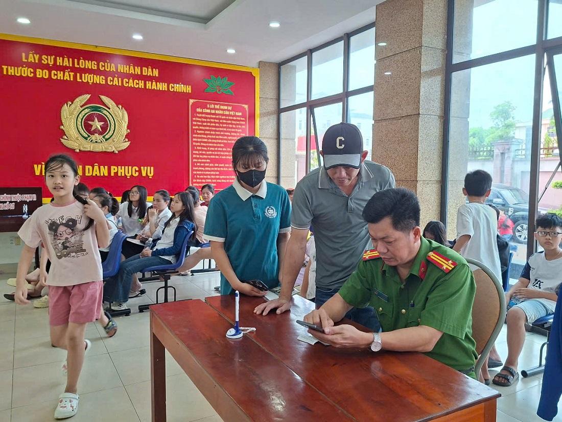 Cán bộ tại Bộ phận một cửa Công an tỉnh hướng dẫn người dân lấy số thứ tự và hướng dẫn người dân đăng nhập định danh điện tử mức độ 2