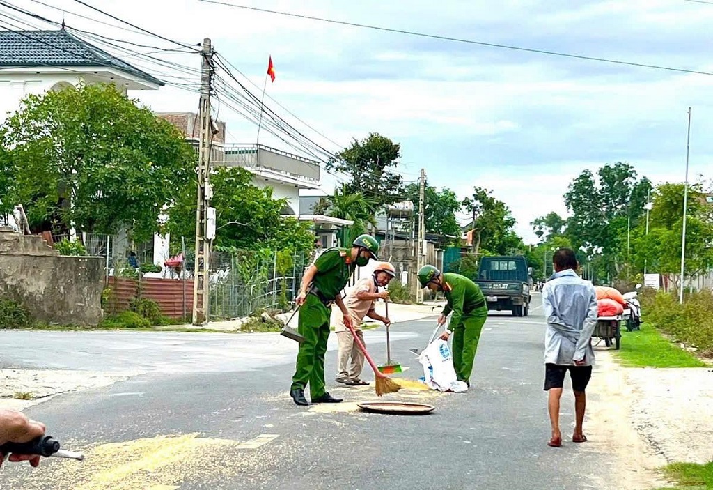 Công an phường Vinh Lộc giúp dân thu dọn thóc lúa đổ ra đường