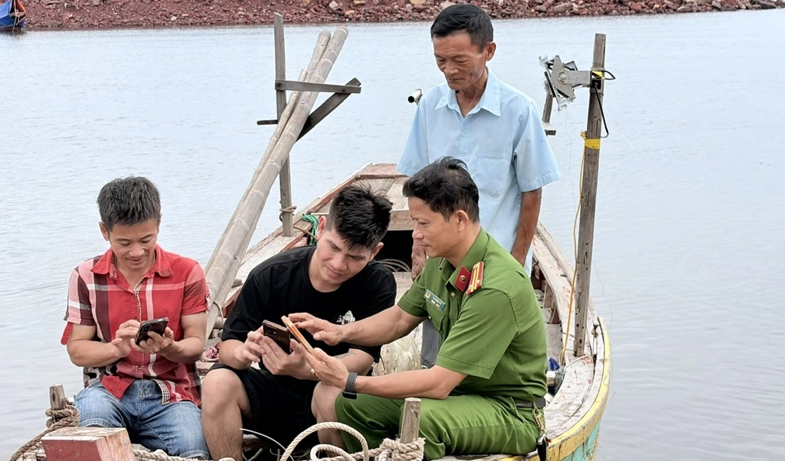 Công an xã Hải Lộc đến tận thuyền của ngư dân tuyên truyền, hướng dẫn và hỗ trợ người dân cài đặt, kích hoạt tài khoản định danh điện tử