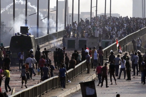 Members of the Muslim Brotherhood and supporters of Mr. Morsi fled tear gas and rubber bullets fired by riot police on a bridge leading to Raba'a al Adiwiya Square in Cairo.