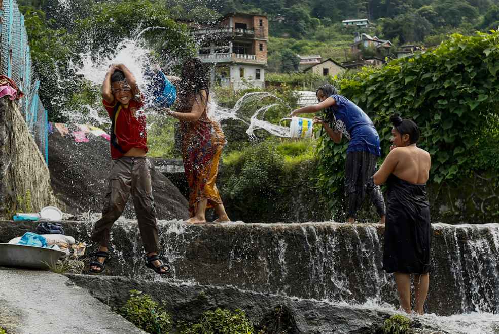 Phụ nữ và trẻ em Nepal tắm trên một thác nước nhỏ ở làng Naryanthan, ngoại ô Kathmandu
