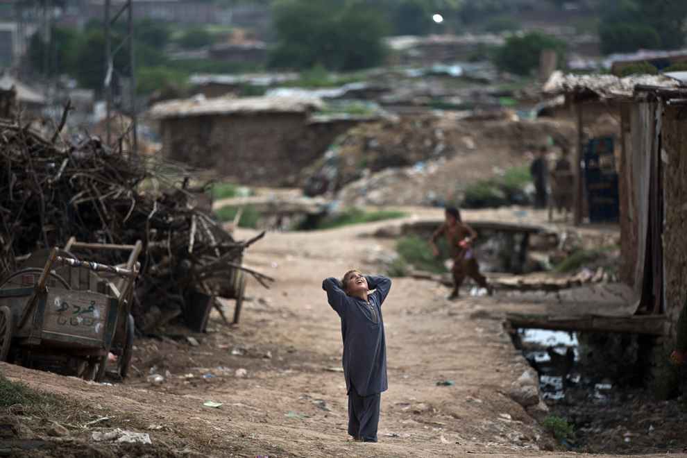 Một cậu bé người Afghanistan đi tị nạn ở Pakistan, ngước mặt lên trời nhìn con diều do một đứa khác thả ở ngoại ô Islamabad