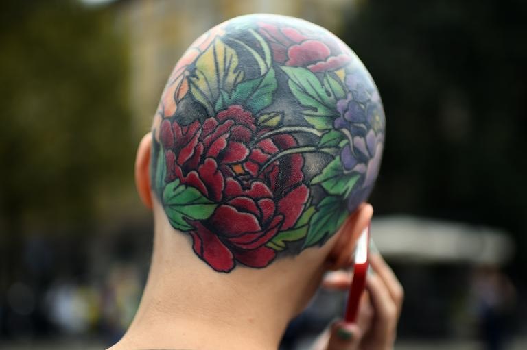 Một du khách với hình xăm độc đáo nói chuyện điện thoại trên đường tới chương trình Tuần lễ thời trang Milan Xuân/Hè 2015