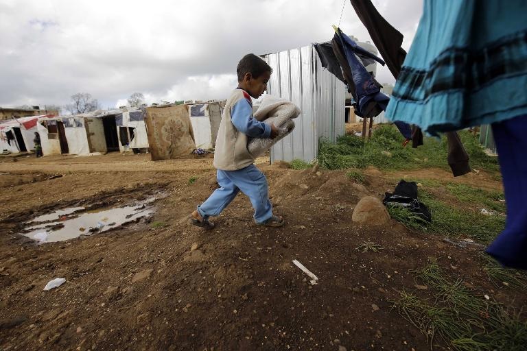 Một đứa trẻ Syria nhận quần áo được cấp phát tại một trại tị nạn ở làng al-Bireh, phía bắc thành phố cảng Tripoli, Lebanon