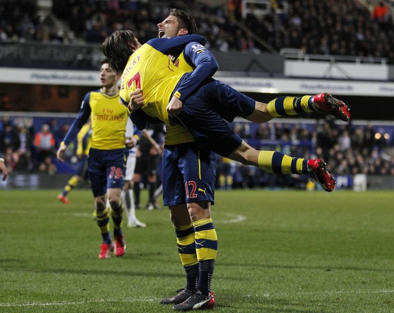 Tiền đạo người Pháp Olivier Giroud của Arsenal (đứng) ăn mừng bàn thắng cùng đồng đội Tomas Rosicky trong trận đấu thuộc khuôn khổ Giải bóng đá Ngoại hạng Anh giữa hai CLB Queen's Park Rangers và Arsenal tại sân vận động Loftus Road ở London
