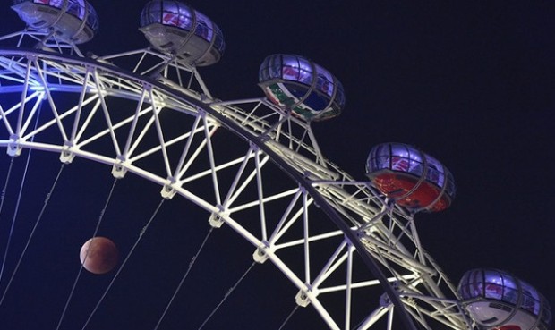 Siêu trăng máu ẩn hiện phía sau các cabin của vòng quay London Eye ở London, Anh.
