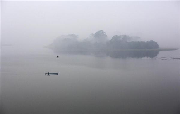 Một người đàn ông chèo thuyền gỗ nhỏ dưới lớp sương sớm trên hồ Inya ở Yangon, Myanmar, 20/02/2016.
